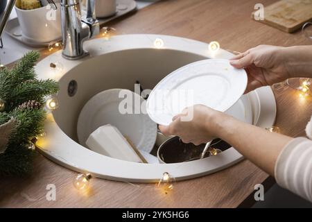 Piatti sporchi nel lavello nella cucina guarnita, una festa dopo una festa di Natale. Disordine dopo gli ospiti per il nuovo anno, la pulizia della cucina, det Foto Stock