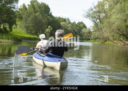 Gita in kayak per tutta la famiglia per il Seigneur e senora. Una coppia di anziani sposati che voga una barca sul fiume, un'escursione in acqua, un'avventura estiva. Sport legati all'età Foto Stock