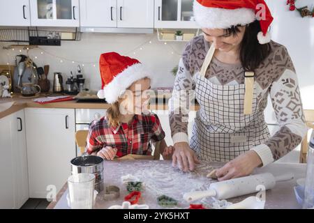 Mamma e figlia nella cucina bianca stanno preparando biscotti per Natale e Capodanno. Giornata di famiglia, preparazione per le vacanze, imparare a cucinare delicio Foto Stock