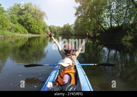 Gita in kayak in famiglia. Mamma e figlia canottano una barca sul fiume, un'escursione in acqua, un'avventura estiva. Eco-friendly e turismo estremo, attivo e sano Foto Stock