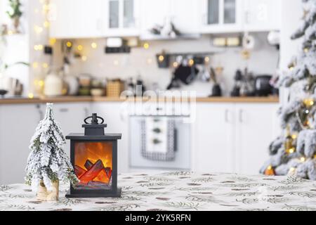 Decorazioni natalizie su un tavolo vuoto rotondo con tovaglie con aghi di pino e stampa a coni in cucina bianca, interni moderni con un tr natalizio Foto Stock