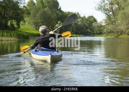 Gita in kayak per tutta la famiglia per il Seigneur e senora. Una coppia di anziani sposati che voga una barca sul fiume, un'escursione in acqua, un'avventura estiva. Sport legati all'età Foto Stock