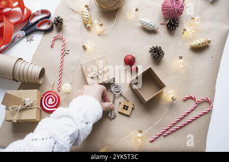 Chiave a casa con portachiavi su accogliente casa in confezione regalo con decorazioni natalizie. Pack presente per Capodanno, Natale. Costruzione, progetto, trasferimento Foto Stock