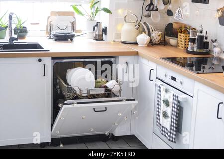 C'erano molti piatti sporchi in lavastoviglie nella cucina festosa. Aiutare la padrona di casa, l'economia e l'ecologia. Pulizia in cucina per le vacanze di Foto Stock