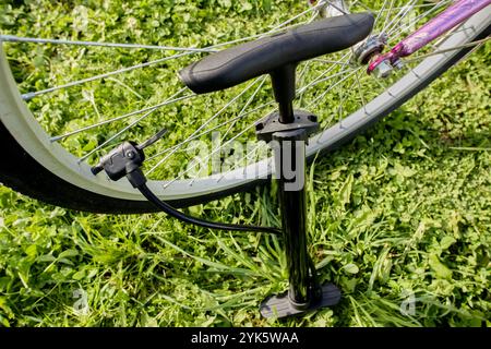 Gonfiare lo pneumatico della bicicletta con aria utilizzando una pompa a pavimento con testa universale dotata di morsetto a leva. Foto Stock