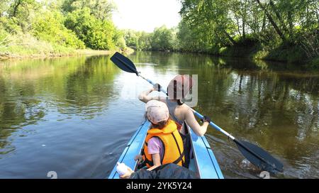 Gita in kayak in famiglia. Mamma e figlia canottano una barca sul fiume, un'escursione in acqua, un'avventura estiva. Eco-friendly e turismo estremo, attivo e sano Foto Stock