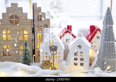 Casa minuscola e chiave di piccole dimensioni in una casa intima con decorazioni natalizie sul davanzale. Regalo per Capodanno. Assicurazione, trasferirsi in una nuova casa, mutuo, affitto Foto Stock