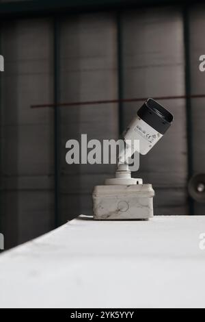 Primo piano di una telecamera di sicurezza a circuito chiuso montata all'interno di un magazzino, che monitora la sicurezza e la sorveglianza. Foto Stock