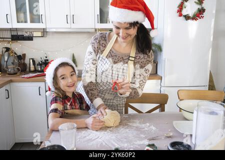 Mamma e figlia nella cucina bianca stanno preparando biscotti per Natale e Capodanno. Giornata di famiglia, preparazione per le vacanze, imparare a cucinare delicio Foto Stock