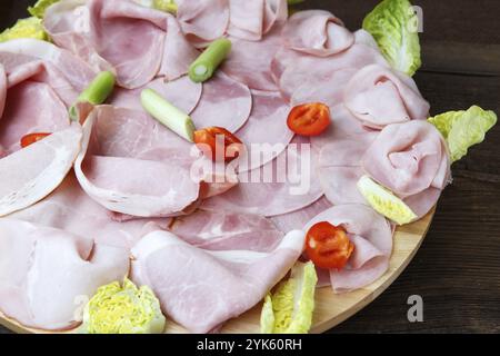 Vassoio con delizioso salame, pezzi di prosciutto a fette, pomodori, insalata e verdure, piatto di carne con selezione Foto Stock