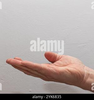 Gesto della mano con il palmo aperto su uno sfondo bianco, che simboleggia l'apertura e l'offerta Foto Stock