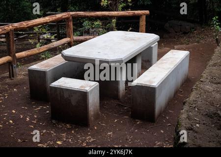 area picnic pubblica nel bosco con tavolo in cemento e panchine vicino al sentiero escursionistico . Foto Stock