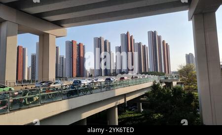 Una scena urbana di Shenzhen, in Cina, che mostra un trafficato cavalcavia con auto e moto sullo sfondo di moderni e alti edifici residenziali. Foto Stock