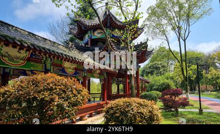 Edificio in stile pagoda con le sue intricate incisioni e colorate pitture spicca sullo sfondo di lussureggianti alberi verdi e di un cielo blu chiaro. Foto Stock