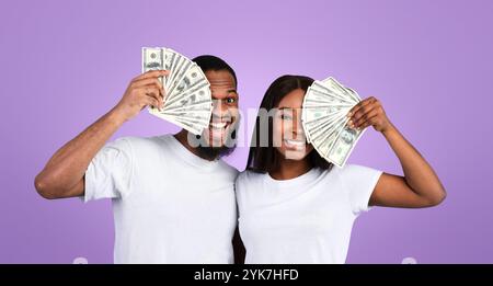 Eccitata coppia afroamericana che tiene un sacco di dollari in contanti Foto Stock
