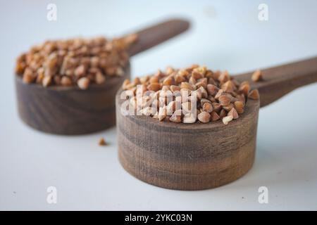 Primo piano di chicchi di grano saraceno in cucchiaio graduato in legno Foto Stock