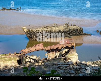 Un relitto arrugginito parzialmente sommerso in sabbia e acqua su una spiaggia di Lanester-Kerhervy, Bretagna Foto Stock