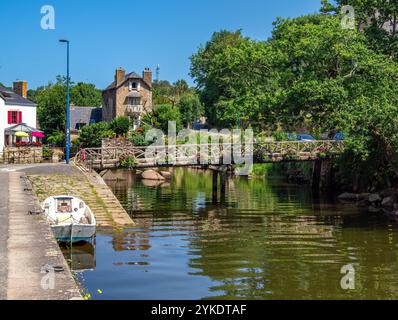 Pont Aven, Francia - 29 luglio 2024: Una pittoresca scena a Pont Aven con un fiume Aven con una piccola barca ormeggiata a fianco. Un ponte di legno, surr Foto Stock