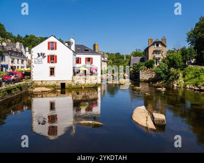 Pont Aven, Francia - 29 luglio 2024: Una pittoresca scena a Pont Aven caratterizzata da un affascinante edificio bianco con accenti rossi accanto a una tranquilla rive del fiume Aven Foto Stock