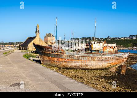 Vecchie barche arrugginite sulla riva di Camaret sur Mer in Bretagna, torre Vauban e chiesa Notre Dame de Roaamadour sullo sfondo Foto Stock