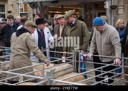 Agricoltore britannico con le sue pecore in piedi nella penna. Il responsabile del collocamento che estrae un’offerta da un rappresentante di uno dei due macellai/acquirenti locali per gli allevatori di ovini che si trovano nelle recinzioni temporanee. Il mercato annuale del bestiame di Natale il mercato iSQUARE n Uppingham, Rutland, Inghilterra 24 novembre 2021 2020s HOMER SYKES Foto Stock