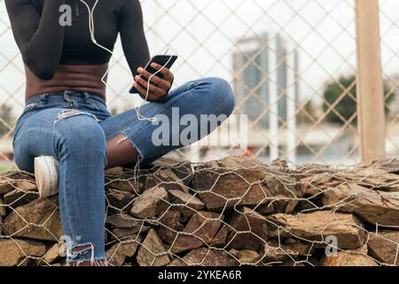 donna nera irriconoscibile che ascolta musica Foto Stock