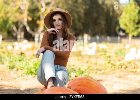 Donna che posa per sedersi sulla zucca in un cerotto di zucca Foto Stock