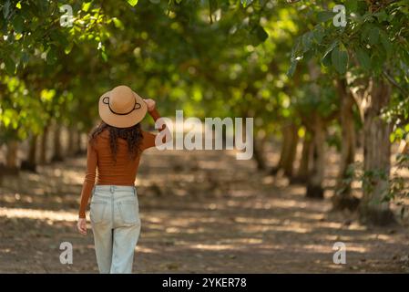 Donna che indossa abete e cappello che cammina circondato da alberi Foto Stock