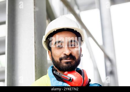 giovane ingegnere con barba e casco in piedi all'esterno Foto Stock