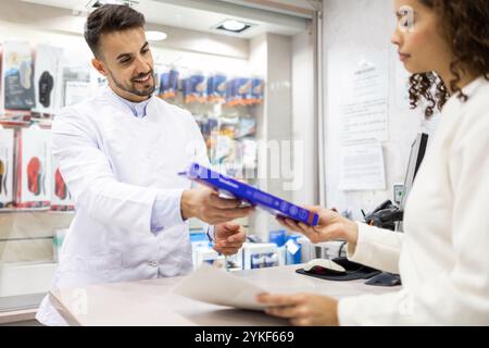 Una persona con un camice bianco assiste un cliente presso un negozio di forniture ortopediche vari prodotti ortopedici sono esposti sugli scaffali Foto Stock