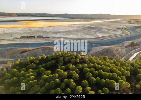 Uno scatto aereo cattura il paesaggio strutturato della miniera di Rio Tinto con linee di alberi contrastanti mentre il sole tramonta a Huelva, in Spagna. Foto Stock