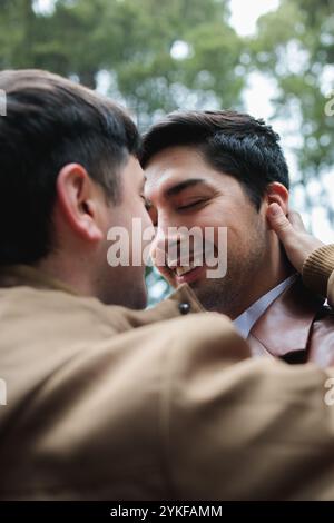 Un momento emozionante condiviso tra una coppia gay, catturato mentre si abbracciano amorevolmente, trasudando felicità e intimità in un ambiente all'aperto Foto Stock