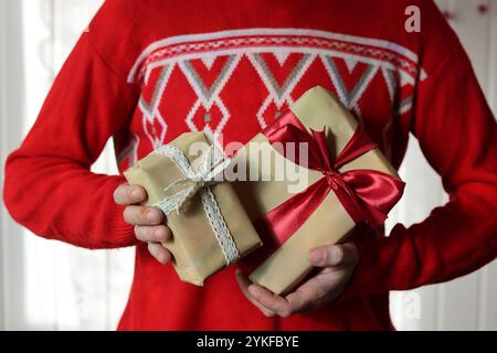 Uomo in maglione rosso con confezione regalo di Natale con nastro rosso. Foto Stock