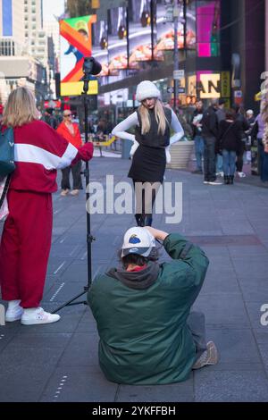 Un fotografo e il suo assistente scattano abiti invernali su un modello piuttosto sottile. Vicino alle scale rosse di Times Square, Manhattan, New York. Foto Stock