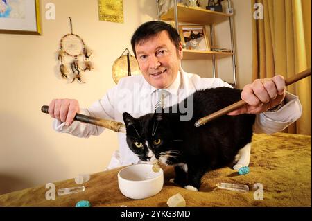 Un medico curante di cristalli che tratta un gatto nero. Foto Stock