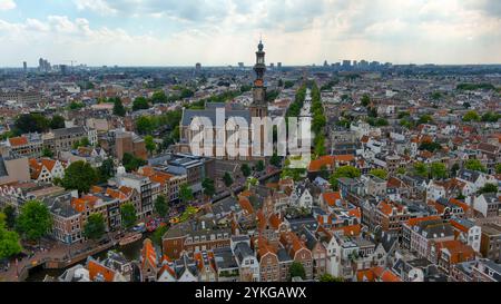 Vista aerea mozzafiato dell'iconica Westerkerk di Amsterdam e delle case sui canali circostanti in un pittoresco ambiente urbano. Foto Stock