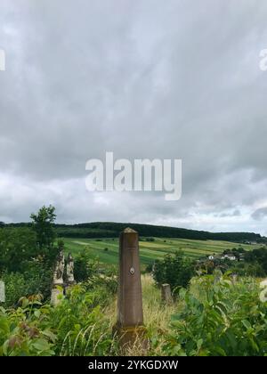 Un affascinante paesaggio rurale caratterizzato da un monumento storico in pietra immerso nel verde sotto un suggestivo cielo nuvoloso. La scena evoca il senso dell'istore Foto Stock