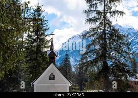 Chiesetta racchiusa nei boschi e sulle cime innevate delle dolomiti nei pressi dell'algo di Dobbiaco in Italia Foto Stock