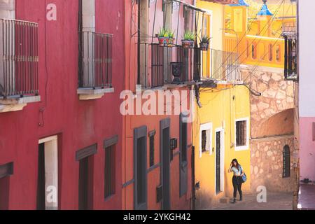 Guanajuato, Messico - 6 febbraio 2024: Giovane donna locale che cammina lungo un vicolo colorato e vivace nella storica città vecchia di Guanajuato. Foto Stock