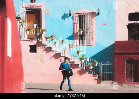 Guanajuato, Messico - 4 febbraio 2024 Una vivace scena nella storica città vecchia di Guanajuato, caratterizzata da un edificio coloniale spagnolo color rosa pastello e blu Foto Stock