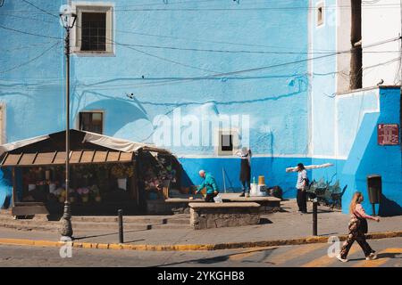 Guanajuato, Messico - 4 febbraio 2024: Vivaci strade di Guanajuato caratterizzate da un edificio blu luminoso, con la gente del posto che segue la routine quotidiana, capturi Foto Stock