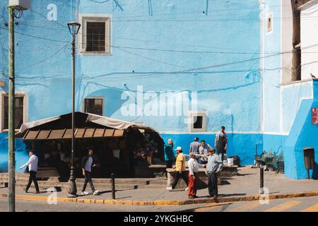 Guanajuato, Messico - 4 febbraio 2024: Vivaci strade di Guanajuato caratterizzate da un edificio blu luminoso, con la gente del posto che segue la routine quotidiana, capturi Foto Stock