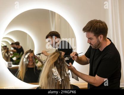 Friseur macht Foliensträhnen bei einer jungen Frau. Il parrucchiere strizza i capelli di una giovane donna Foto Stock