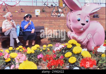 Coppia anziana seduta lungo il lungomare a mangiare gelati. Mablethorpe. Lincolnshire. Inghilterra. REGNO UNITO Foto Stock