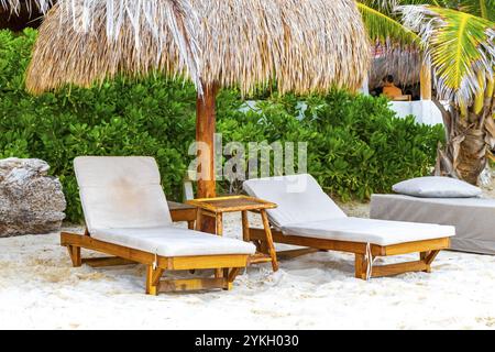 Palapa con tetti di paglia, palme, ombrelloni e sedie a sdraio presso l'hotel Beach Resort sulla spiaggia tropicale messicana di Playa del Carmen, Messico Foto Stock