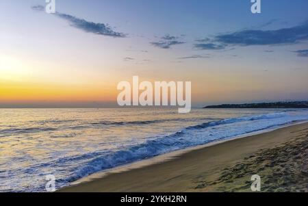 Bellissimo tramonto colorato e dorato in giallo arancio rosso sulla spiaggia e grande enorme panorama onda surfista nella natura tropicale a Zicatela Puerto es Foto Stock