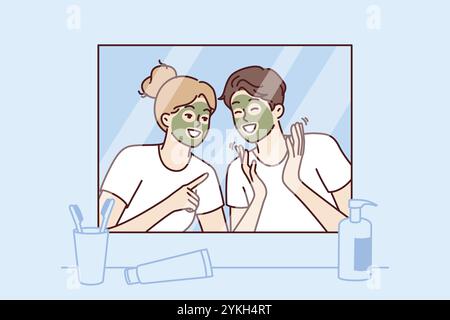 Coppia allegra con maschera ringiovanente sul viso guardare allo specchio e ridere godendo una vacanza congiunta. Mattina giovane uomo felice e donna con maschera per reju Foto Stock