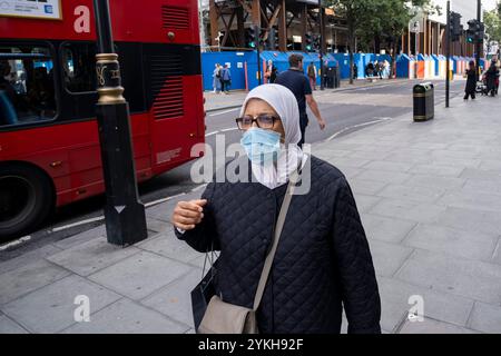 Donna che indossa una maschera per proteggere contro il Coronavirus / Covid-19 su Oxford Street il 7 ottobre 2024 a Londra, Regno Unito. L'uso delle coperture facciali nei luoghi pubblici è molto ridotto poiché i tassi di infezione sono diminuiti e la paura della pandemia è diminuita. Nonostante questo, l'uso della maschera continua ancora in qualche misura. Foto Stock