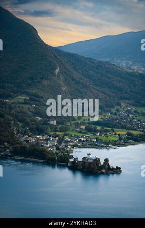 Vista ad alto angolo di Château de Duingt sul lago di Annecy, circondata dalle verdi colline in una luce soffusa Foto Stock