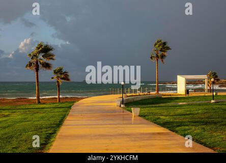 Ammira il percorso costiero di Paphos, con nuvole di pioggia scure in lontananza, Paphos, Cipro. Foto Stock